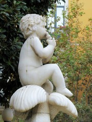 estatua de niño flautista con fondo arbolado en otoño