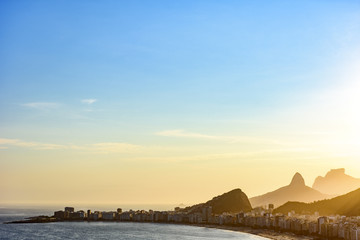 Obraz premium Copacabana beach in Rio de Janeiro during sunset with its buildings and the mountains in the background
