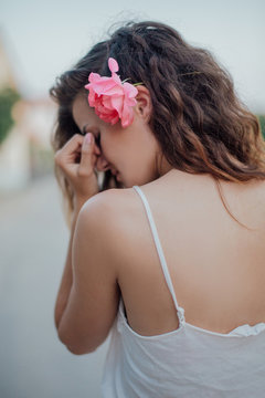 Girl with summer brown curly hair hiding her face