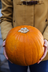 Close-up of young woman holding orange pumpkin