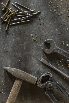 Different hand tools, nails and screws on dark metal background