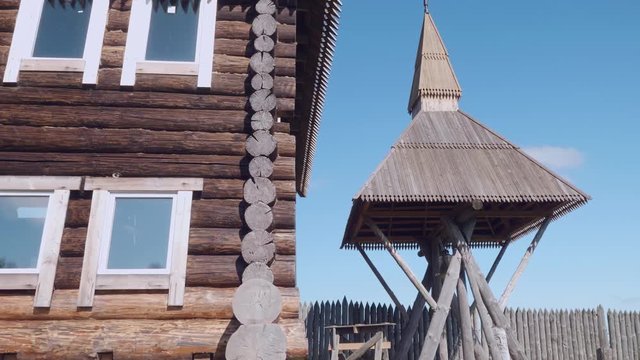 Wooden bell tower with old wooden russian house at left