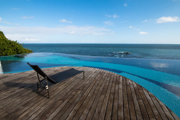 infinity pool with beach chair on the wooden deck