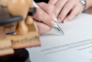 Sekretärin unterschreibt im Büro ein Schriftstück – selektive Schärfe und viel Copyspace für...