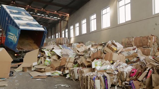 Warehouses with recyclable materials at the garbage processing factory. Truck brought the waste paper to the garbage processing plant. Large warehouse of waste paper in a factory.