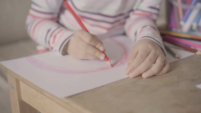 preschool girl drawing a picture with red pencil close-up