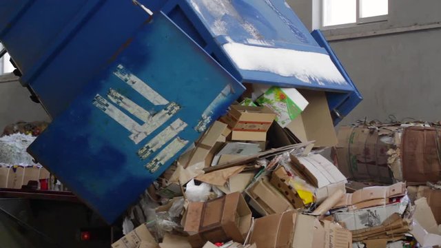Truck brought the waste paper to the garbage processing plant. Unloading of recyclable materials in the warehouse of the waste processing plant.