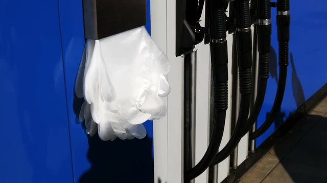 Polyethylene gloves hang at the gas station next to a gasoline pistol
