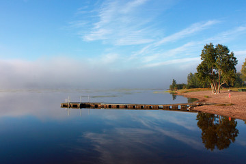 Water and dock  reflection at lake in foggy morning