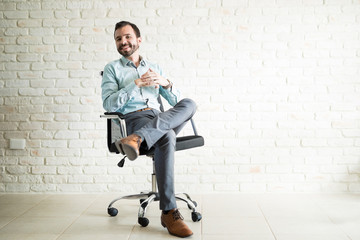 Handsome Latin freelancer sitting on a chair in a studio
