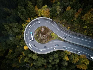 Fototapete Rund street from above trough a misty forest at autumn, aerial view flying through the clouds with fog and trees © visualitte