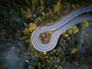 Fotobehang Luchtfoto straat van bovenaf door een mistig bos in de herfst, luchtfoto vliegend door de wolken met mist en bomen