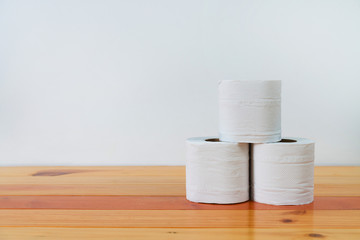 Fototapeta na wymiar White tissues paper or toilet paper on wooden table over white wall.