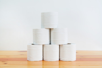 White tissues paper or toilet paper on wooden table over white wall.