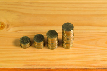 Savings, increasing columns of gold coins, piles of gold coins arranged as a graph on wooden table.