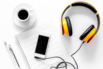 Worktable of composer today. Headphones, phone, music notes on white background top view