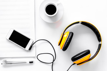Worktable of composer today. Headphones, phone, music notes on white background top view