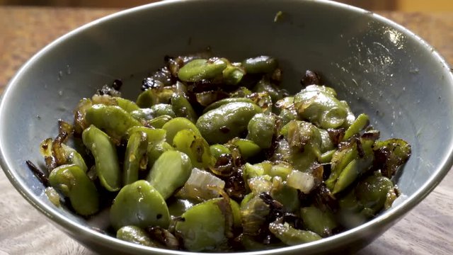 Cooked fava beans with onion and caramelized onions rotating