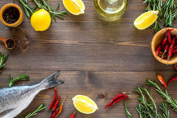 Mediterranian cuisine. Dorado with rosemary, pepper, chili, lemon on wooden background top view copyspace