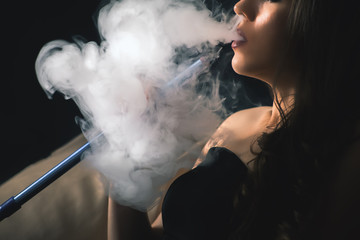 Young, beautiful girl smoke a hookah at club © petunyia
