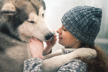 Image of young girl feeding her dog, alaskan malamute, outdoor