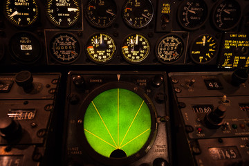 Airplane green glowing radar with aircraft gauges, switches, and knobs