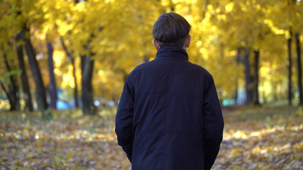 young guy in a black coat in the autumn park.