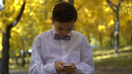 Fototapeta premium young guy playing in the phone and walking in the autumn park.