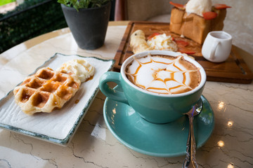 Cappuccino ,Waffle and Honey Toast with banana strawberrie icecream and honey Placed on a table in a coffee shop.High calorie.Dessert for women and Children love