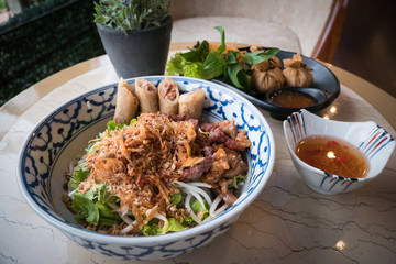 Vietname food in the restaurant in the evening.There are noodles, fried meat and vegetable.