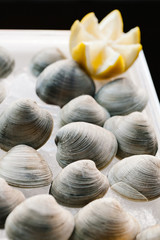 An assortment of raw clams on ice garnished with lemon