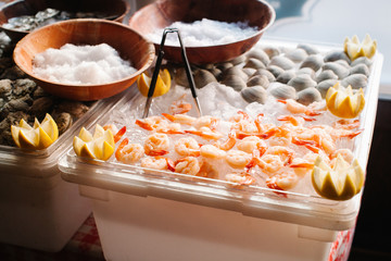 An assortment of cooked shrimp and raw clams on ice garnished with lemon