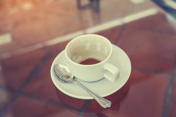 cup with leftover coffee on desk, in soft focus with vintage filter
