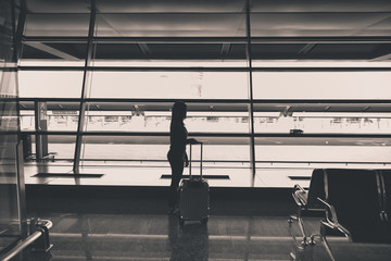 Passenger with carry on luggage waiting for the delay flight at the gate in the airport terminal,black and white toned