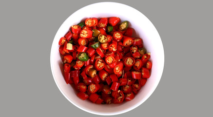 Isolated Sliced Thai Chilies in White Bowl on Gray Background