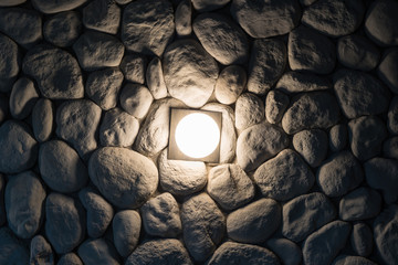 Bright wall lamp on dark stone wall at night