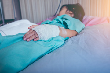 Illness asian child admitted in hospital with saline intravenous on hand.