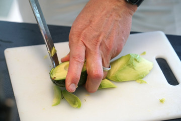 Man cutting avocado on the board by knife