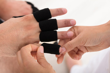 Doctor Putting Finger Protector Sleeve On Man's Finger