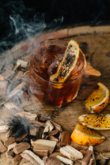 Smoked old fashioned cocktail on dark wooden background