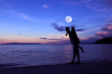 Silhouette father and daughter on the beach with the moon and blue sky