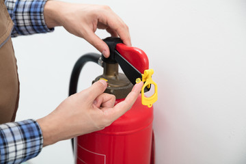Technician's Hand Pointing To Symbol On Red Fire Extinguisher