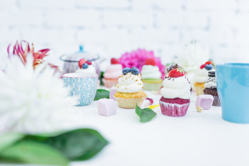 Cupcakes with fresh berries flowers and leaves, a cup of tea or coffee.