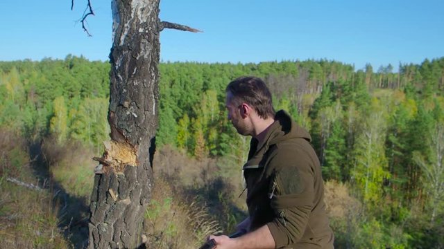 Lumberjack worker chopping down a tree breaking off many splinters in the forest with big axe. Strong healthy adult ripped man with big muscles working with big axe outdoors