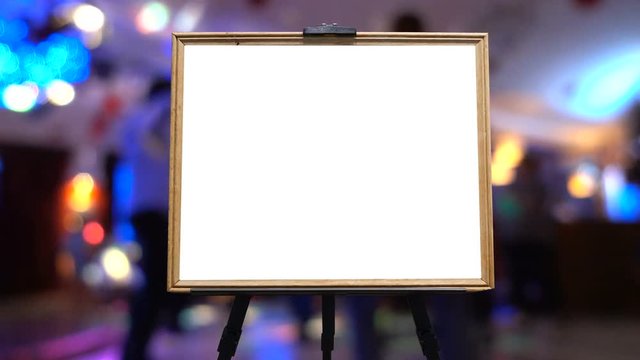 In the background, blurred and defocused images of dancing people in a restaurant or a nightclub. In the foreground is a wooden frame as a place for your text or logo.