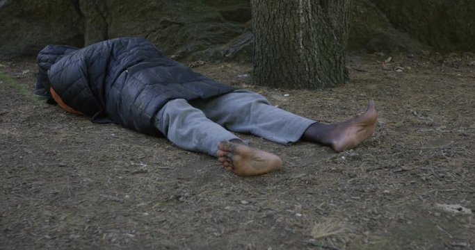 Homless man sleeping wiggles toes in central park - New York City September 13th 2017