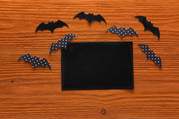 Empty paper card with decorative bats on orange wooden background. Space for text.
