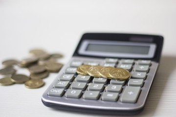 Money concept. Calculator with coins on wooden table