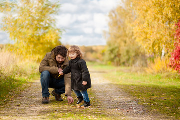 Naklejka na ściany i meble Father and daughter walking together, autumn day.