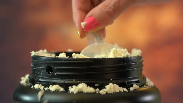 Macro close up of woman leaving scoop in container of  pure nutritional supplement whey protein powder